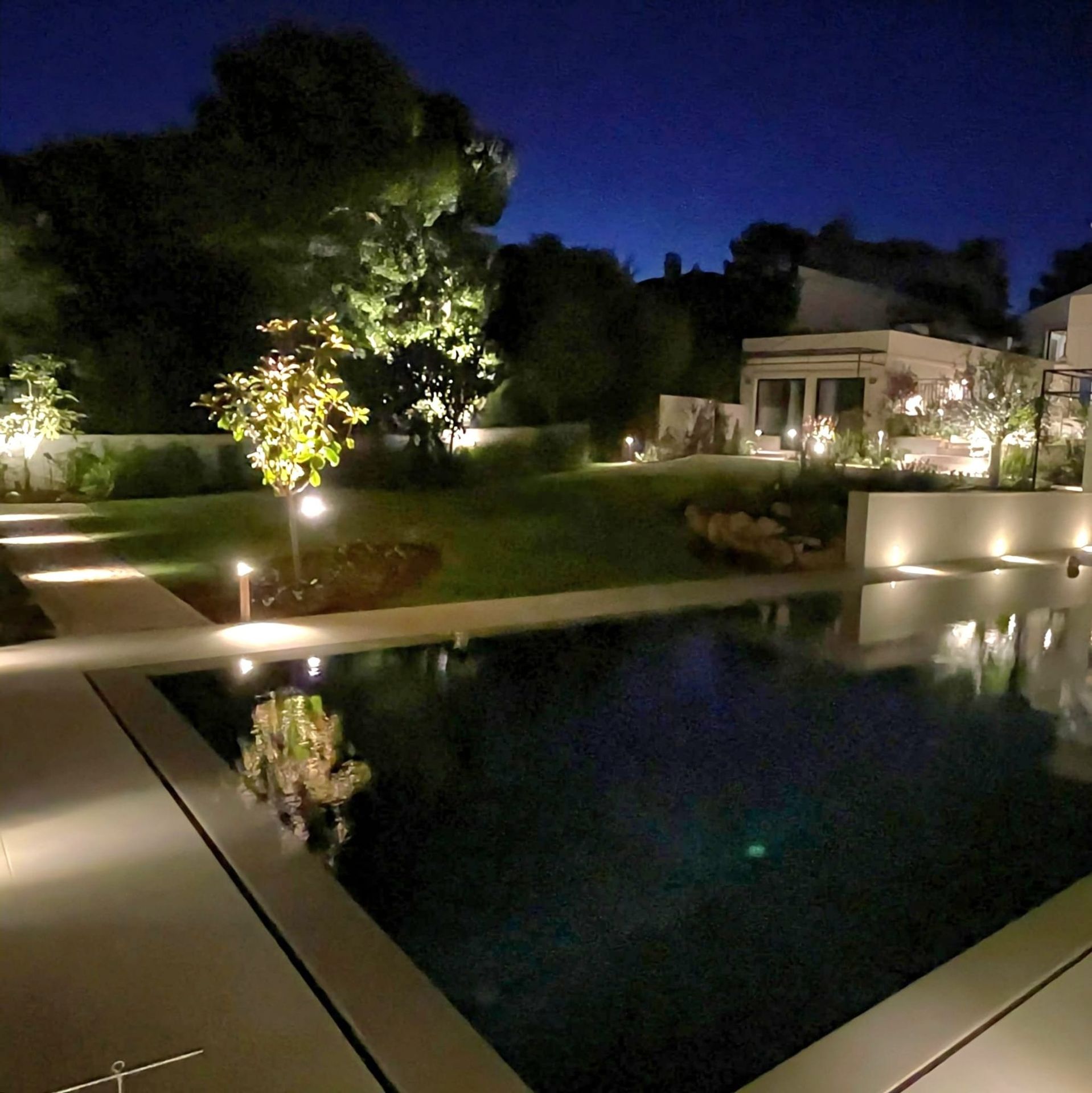 A pool and a house reflected in the water at night