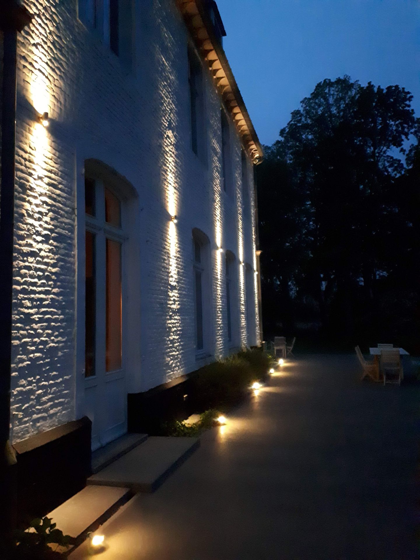 Wall lights along a pale façade at night